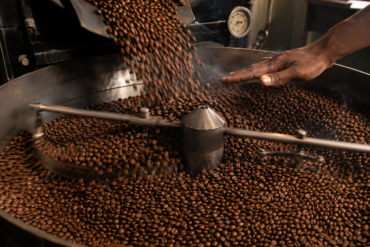 Photo of freshly roasted beans cascading into the cooling tray, stirring arms rotating with motion blur