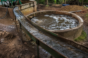 Photo of the circular concrete skin-water basin in the bare-earth mill yard